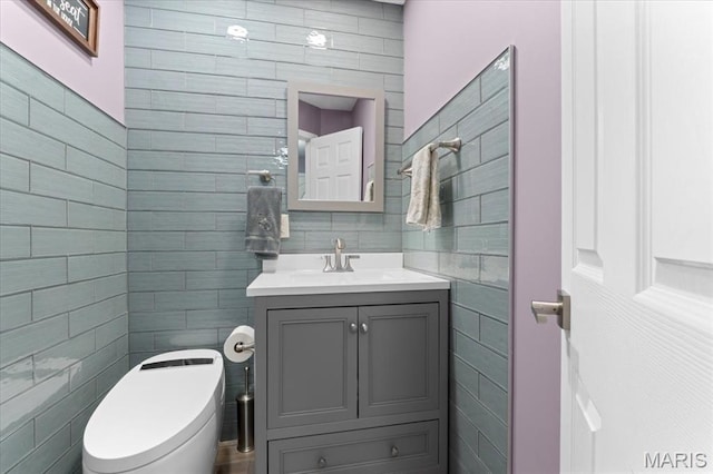 bathroom with tile walls, toilet, and vanity