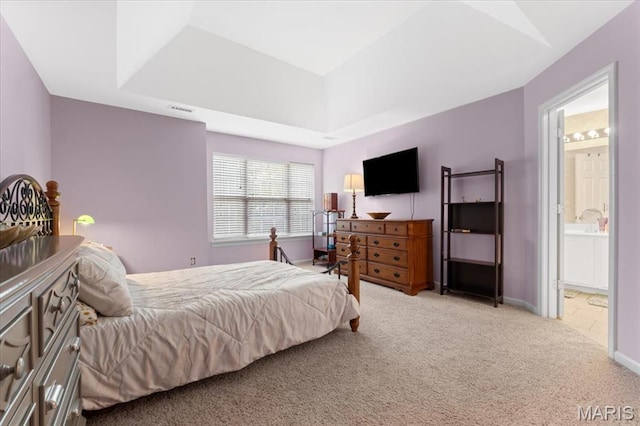 bedroom with light carpet, a tray ceiling, ensuite bathroom, and baseboards