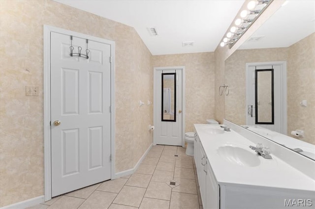 bathroom with tile patterned flooring, baseboards, toilet, and double vanity