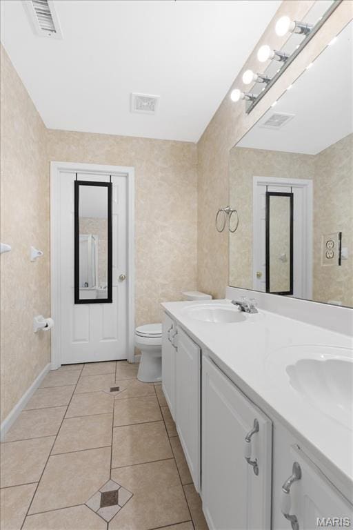 bathroom with tile patterned floors, toilet, double vanity, and baseboards