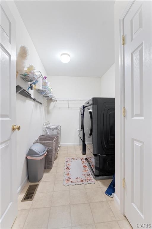 clothes washing area with washer and clothes dryer, tile patterned flooring, and baseboards