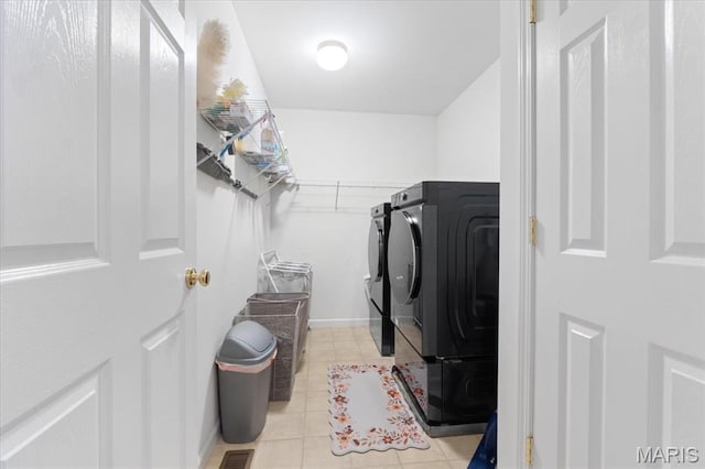 clothes washing area with washer and dryer and light tile patterned floors