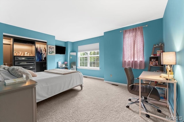 bedroom featuring carpet, a closet, baseboards, and a desk