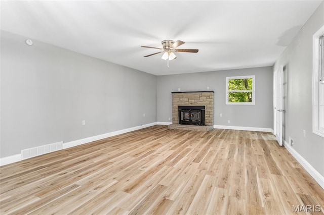 701 Hillsboro Rd, Farmington, MO 63640 - unfurnished living room with a ceiling fan, light wood-style flooring, a stone fireplace, and baseboards