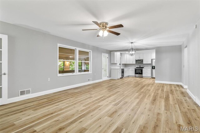 701 Hillsboro Rd, Farmington, MO 63640 - unfurnished living room featuring ceiling fan, light wood-style floors, baseboards, and a chandelier