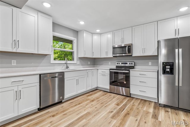 701 Hillsboro Rd, Farmington, MO 63640 - kitchen with appliances with stainless steel finishes, a sink, light countertops, white cabinets, and light wood-style floors