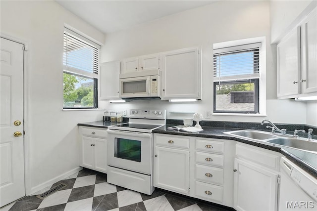10 N Taylor Ave # 1S, Saint Louis, MO 63108 - kitchen featuring white appliances, a sink, white cabinetry, dark countertops, and baseboards
