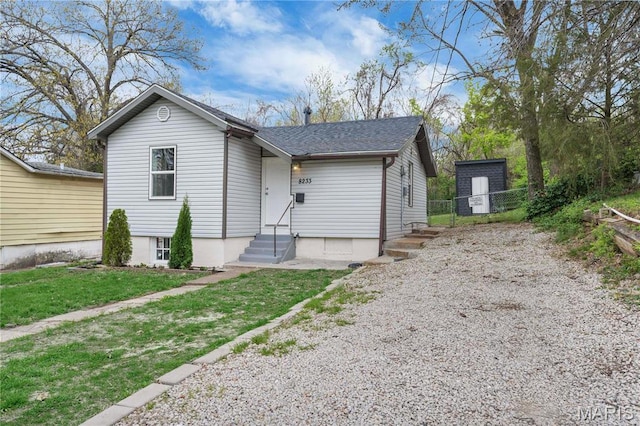 view of front of property with gravel driveway, fence, entry steps, and roof with shingles