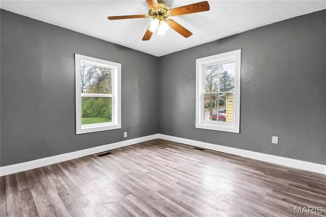 unfurnished room featuring wood finished floors, ceiling fan, baseboards, and a textured ceiling
