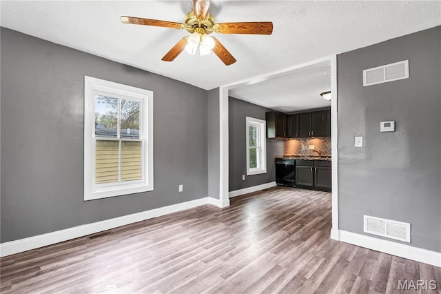 unfurnished living room featuring plenty of natural light, wood finished floors, and baseboards