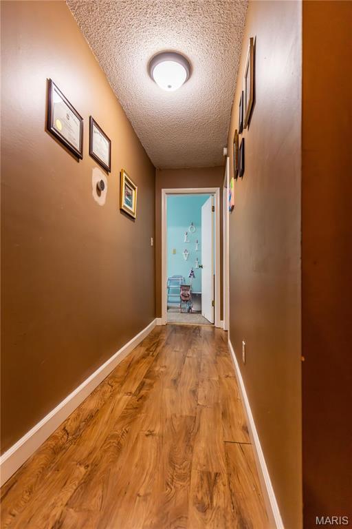 211 E Elm, Bertrand, MO 63823 - corridor featuring a textured ceiling, light wood finished floors, and baseboards