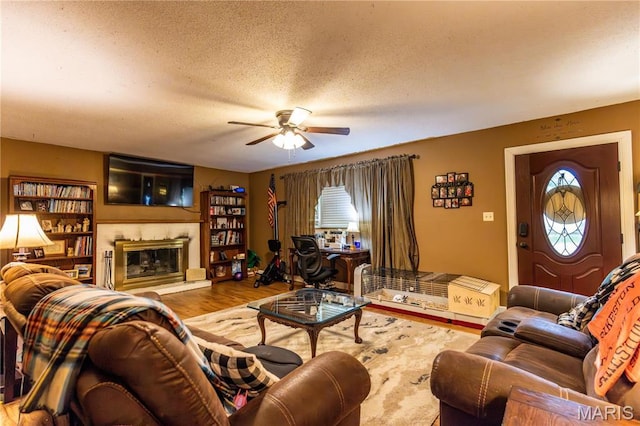 211 E Elm, Bertrand, MO 63823 - living room featuring a ceiling fan, a textured ceiling, wood finished floors, and a glass covered fireplace