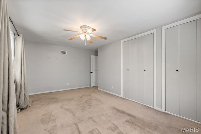 1 Woodoaks Trl, Saint Louis, MO 63124 - unfurnished bedroom with multiple closets, light colored carpet, baseboards, and ceiling fan