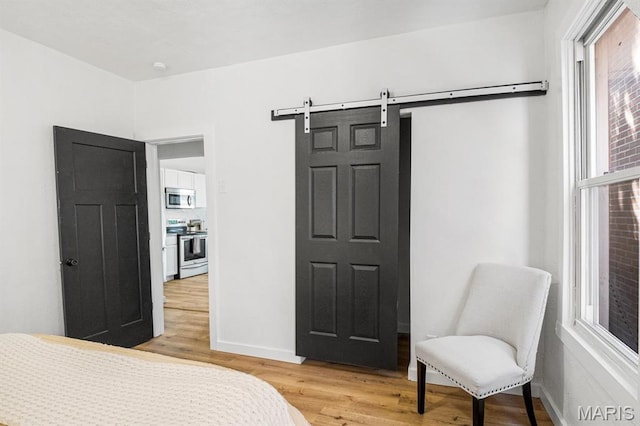 3641 Virginia Ave, Saint Louis, MO 63118 - bedroom with light wood-type flooring, a barn door, and baseboards