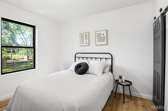 3641 Virginia Ave, Saint Louis, MO 63118 - bedroom featuring a barn door, baseboards, and wood finished floors