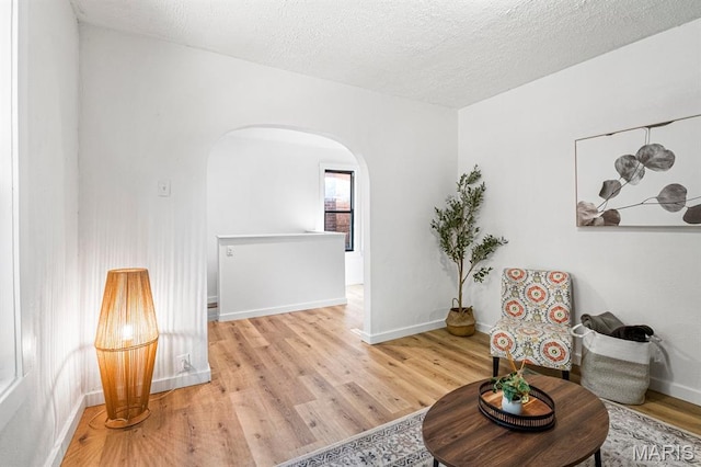 3641 Virginia Ave, Saint Louis, MO 63118 - living area with arched walkways, wood finished floors, baseboards, and a textured ceiling