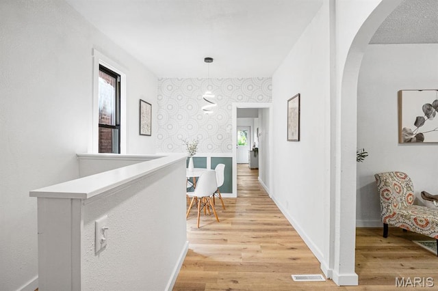 3641 Virginia Ave, Saint Louis, MO 63118 - hallway with arched walkways, light wood finished floors, baseboards, and wallpapered walls