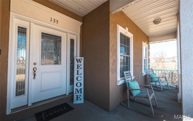 doorway to property with a porch and stucco siding