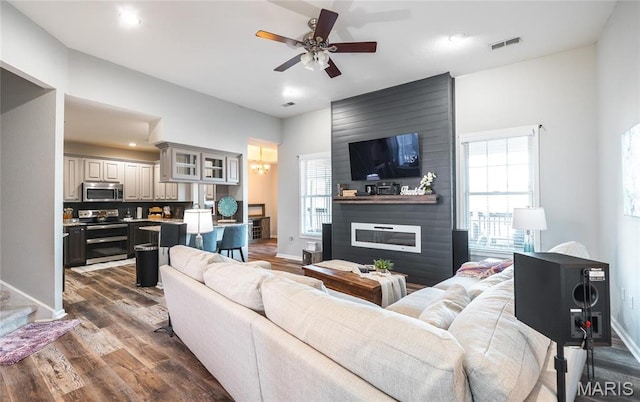 living area featuring dark wood-type flooring, ceiling fan, baseboards, recessed lighting, and a fireplace