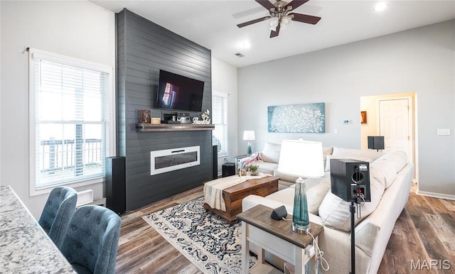 living room featuring a fireplace, a ceiling fan, dark wood-type flooring, baseboards, and recessed lighting