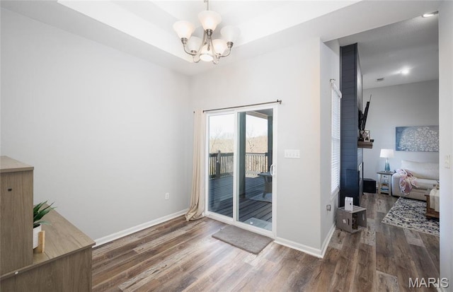 unfurnished room with wood finished floors, a chandelier, and baseboards