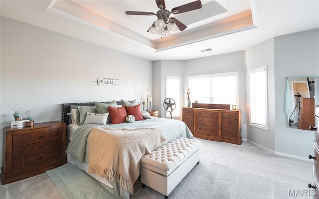 bedroom with a tray ceiling, light carpet, and a ceiling fan