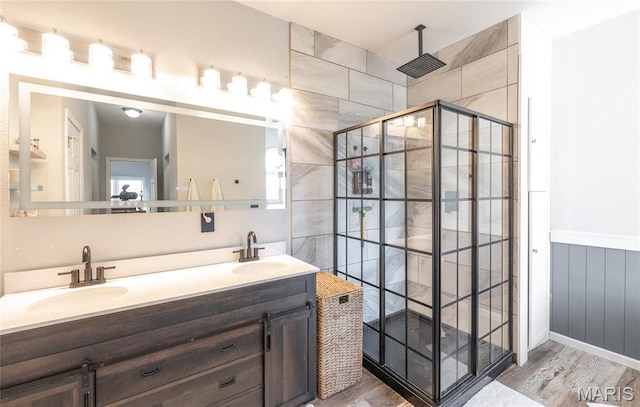 bathroom with tiled shower, wood finished floors, and double vanity