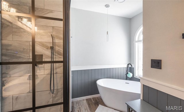 full bathroom with a wainscoted wall, a freestanding bath, wood finished floors, and a tile shower