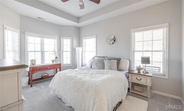 bedroom featuring light colored carpet, baseboards, ceiling fan, and a raised ceiling