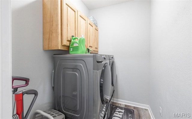 laundry area with independent washer and dryer, cabinet space, baseboards, and wood finished floors