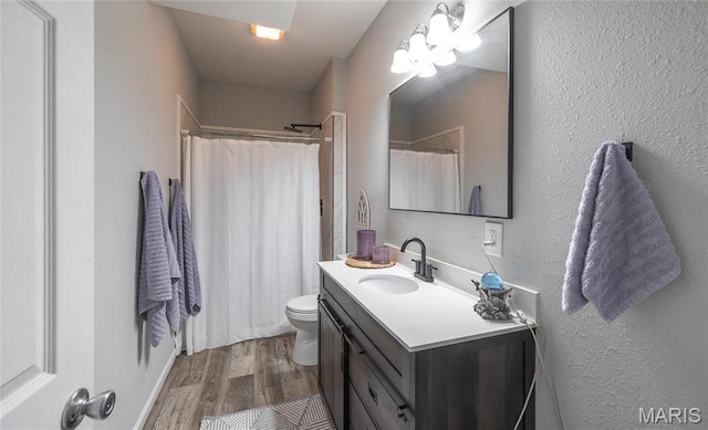 bathroom with wood finished floors, toilet, vanity, and curtained shower