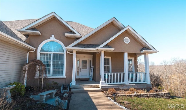 view of front of property featuring a porch, stucco siding, and a shingled roof