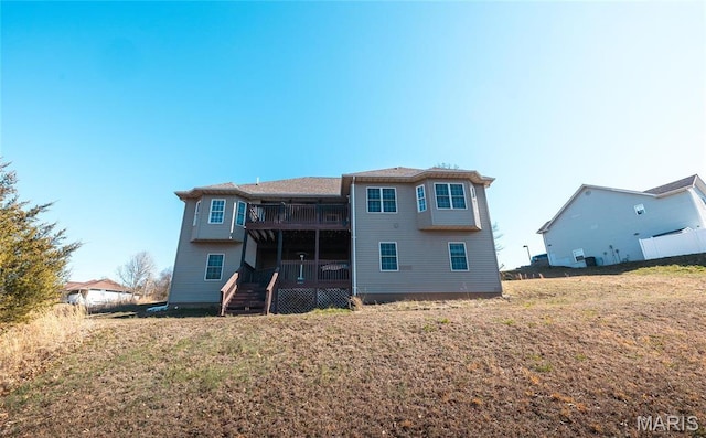 rear view of house featuring a deck, a balcony, and a yard