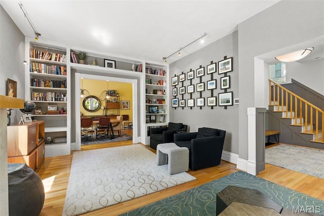 sitting room featuring track lighting, wood finished floors, built in features, and stairs