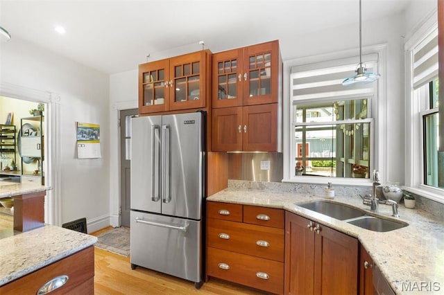 kitchen featuring high quality fridge, a sink, plenty of natural light, and light wood-type flooring