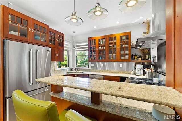 kitchen featuring stainless steel appliances, a sink, glass insert cabinets, light stone countertops, and hanging light fixtures