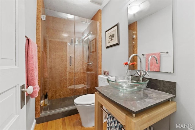 bathroom with toilet, wood finished floors, a shower stall, and vanity