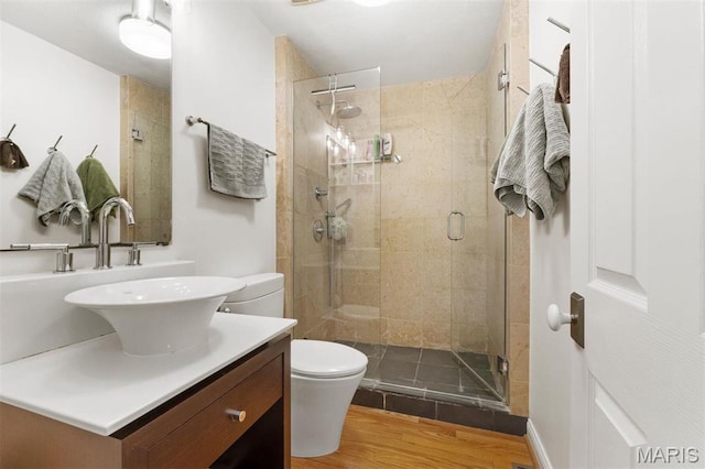 full bathroom with a shower stall, toilet, vanity, and wood finished floors