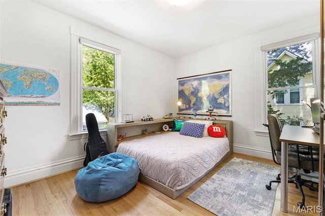 bedroom featuring wood finished floors, baseboards, and a desk