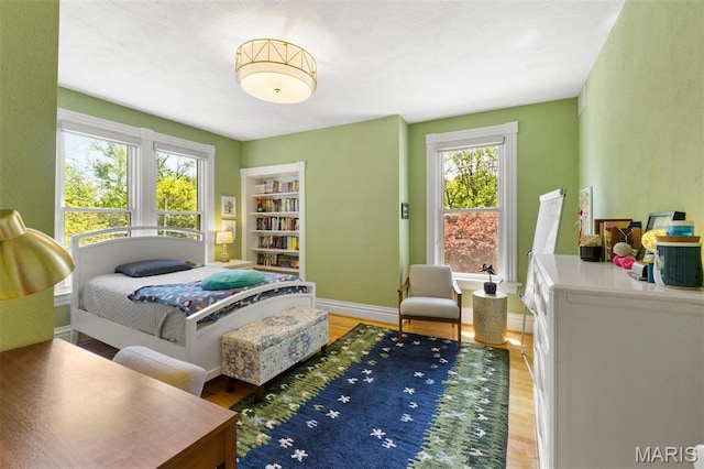 bedroom featuring light wood finished floors and baseboards