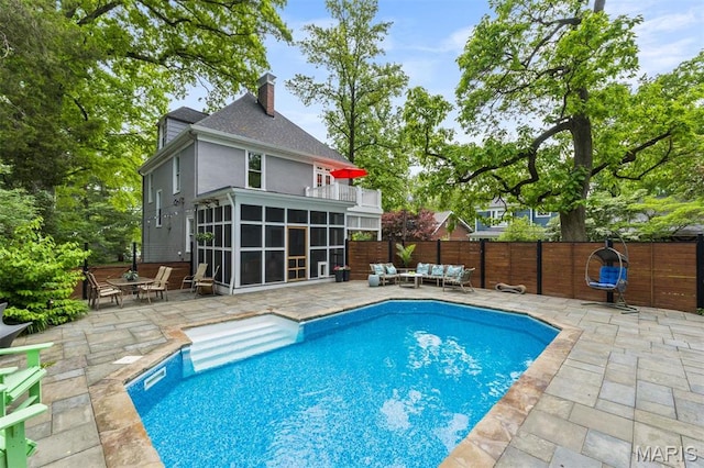 view of pool with a sunroom, an outdoor hangout area, a patio, and fence