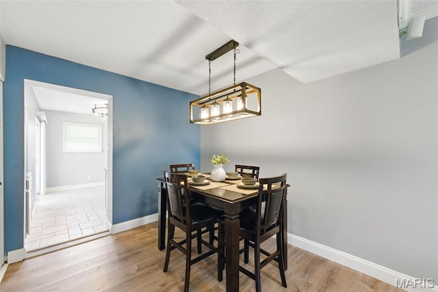 dining area with baseboards, wood finished floors, and a chandelier