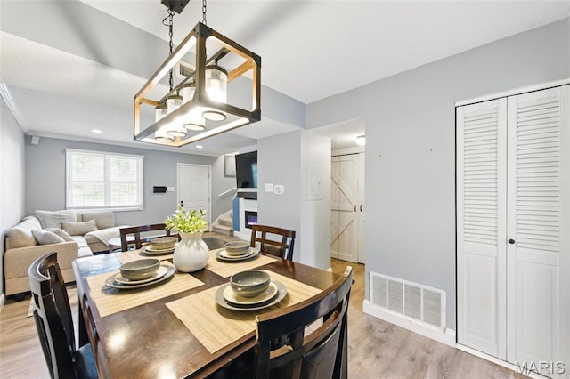 dining space featuring light wood-style flooring, stairway, and baseboards