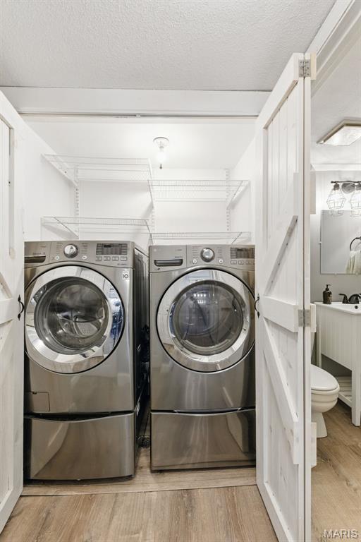 washroom featuring washer and clothes dryer, wood finished floors, and a textured ceiling