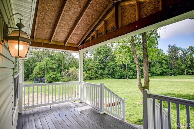 wooden deck featuring a lawn and view of wooded area