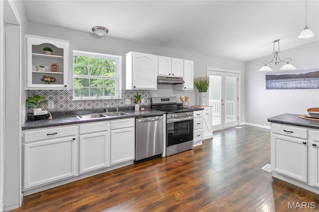 kitchen featuring stainless steel appliances, under cabinet range hood, dark countertops, a sink, and white cabinetry