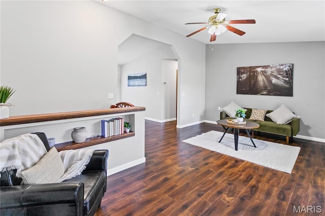 living room featuring arched walkways, ceiling fan, wood finished floors, and baseboards