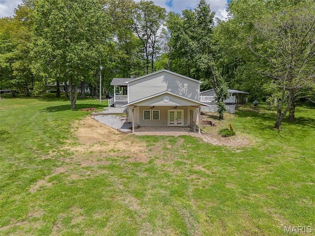 rear view of property featuring french doors, a yard, a porch, and view of wooded area