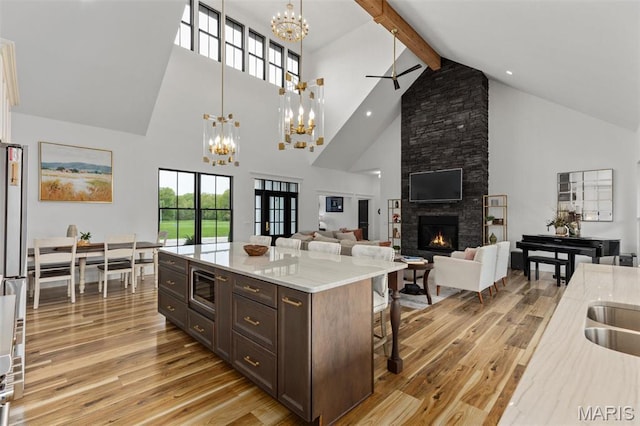10028 Pineridge Dr, Effingham, IL 62401 - kitchen with a chandelier, light wood-style flooring, high vaulted ceiling, a stone fireplace, and a breakfast bar