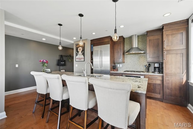 232 N Kingshighway Blvd Unit 907, Saint Louis, MO 63108 - kitchen featuring wall chimney exhaust hood, built in refrigerator, decorative backsplash, an island with sink, and light wood-style flooring